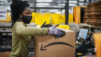 An Amazon warehouse worker holds a delivery package.