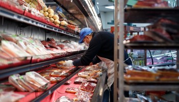 Wearing a mask, an employee stocks the meat section at Greenland Market on April 23, 2020, in Dearborn Heights, Michigan.