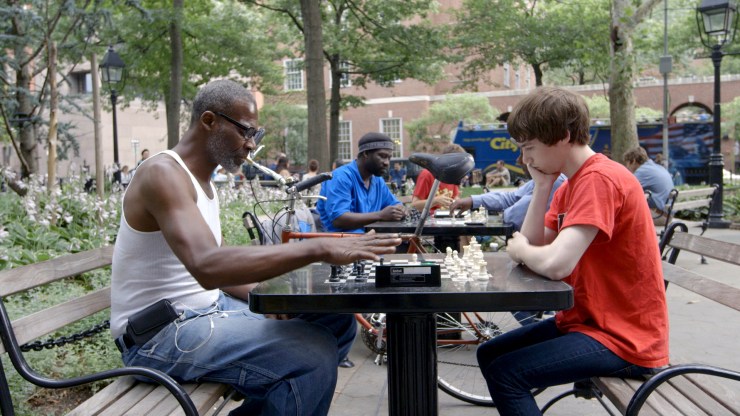 A still from "The Prison in Twelve Landscapes" shows Nahshon Thomas, a formerly incarcerated man who teaches chess in Washington Square Park in New York City, playing at a table.
