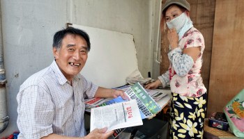Gao Dongde (left) has been buying newspapers from Qu Yali's family for decades. He no longer lives in the neighborhood but he still comes to pick up his newspapers from Qu because there are no news stands near his current home.