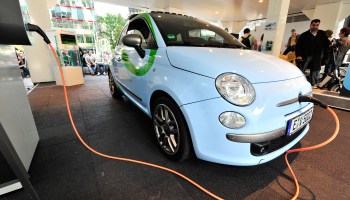 A Fiat 500 with an electric motor gets charged at a car show.