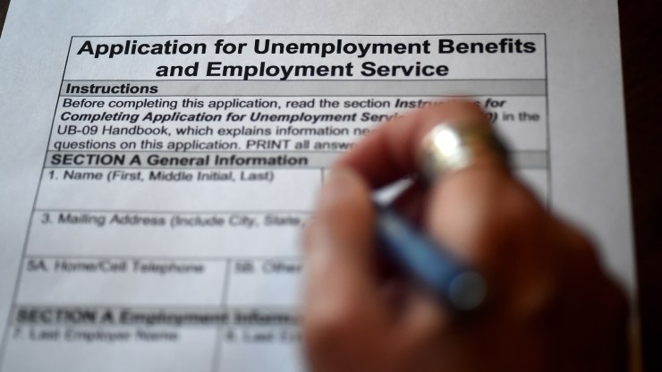 In this photo illustration, a person files a paper application for unemployment benefits.