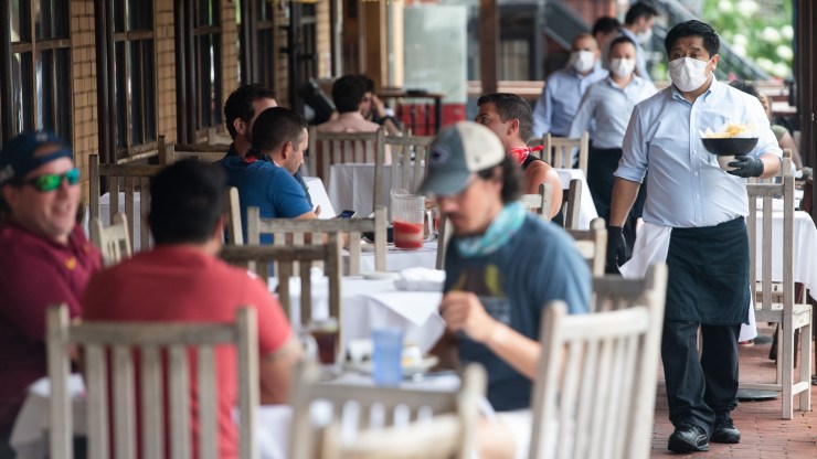 A line of waiters wait on outdoor diners.