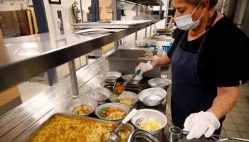 A cafeteria worker prepares lunch for students.