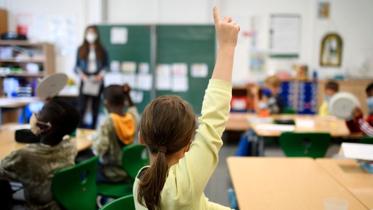 A student raises her hand in a classroom.
