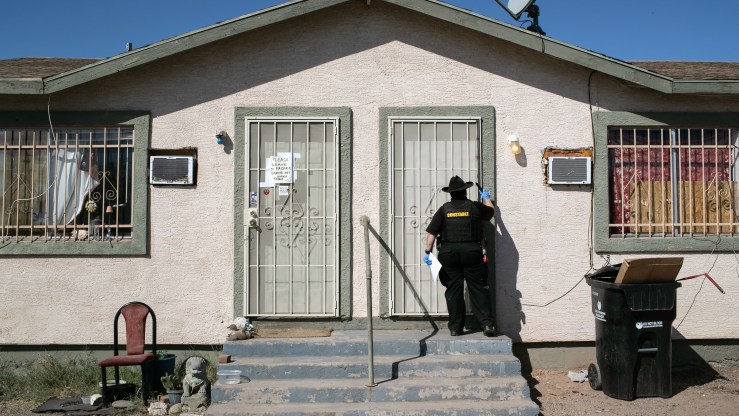 A constable in Maricopa County, Arizona, knocks on a door before posting an eviction order.
