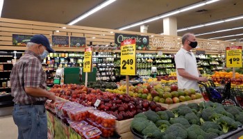 Customers shop for produce at a supermarket.