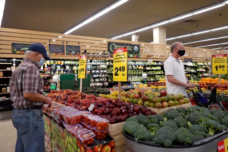 Customers shop for produce at a supermarket.