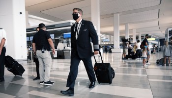 A masked pilot walks through La Guardia Airport in New York.