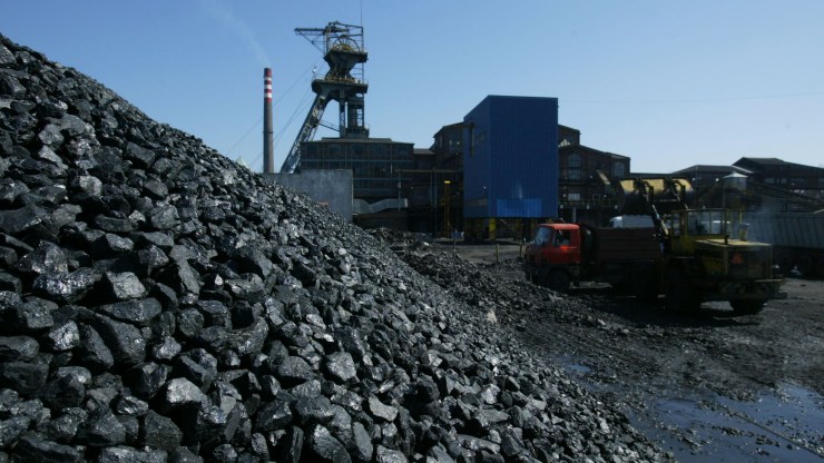 An earth mover loads a truck with coal.