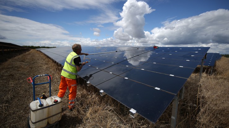A man conducts maintenance on a large set of solar panels.