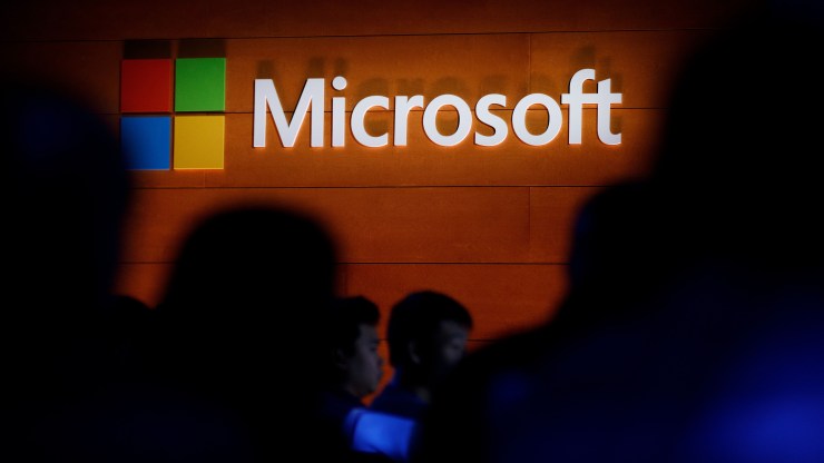 The Microsoft logo is shown behind the silhouette of a crowd.