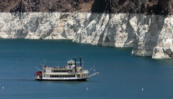Tourists in a paddle boat on Lake Mead. A white "bathtub ring" around the lake shows how low the water level is.