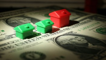 In this photo illustration miniature houses from a Monopoly board game can be seen next to American Dollar notes .