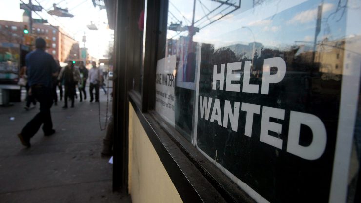 A "Help Wanted" sign is displayed in the window of a storefront.