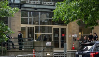 Police officers stand outside of the Seattle Police Department's West Precinct back in June 2020.