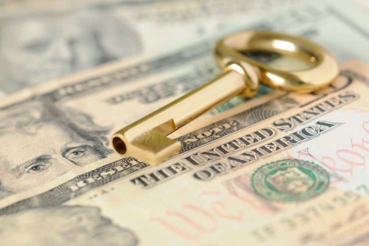 A gold key sits on top of paper money.