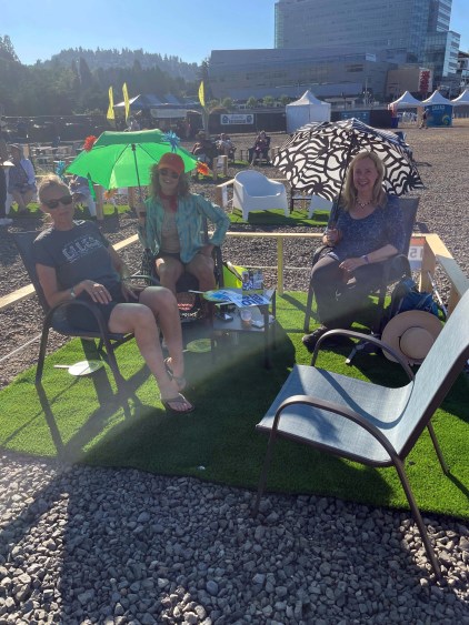 A group of concertgoers sit in patio chairs on AstroTurf at the 2021 Waterfront Blues Festival in Portland, Oregon.