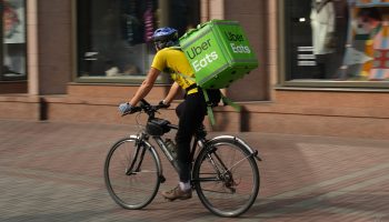 An Uber Eats delivery person hauls the goods while riding a bicycle.