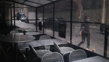 People walk by an empty restaurant in the Financial District in lower Manhattan.