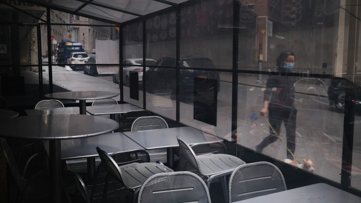 People walk by an empty restaurant in the Financial District in lower Manhattan.