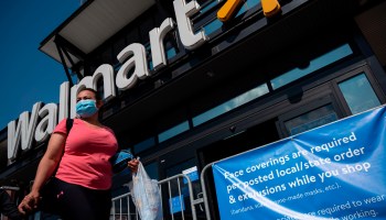 A woman wearing a facemask walks past a sign informing customers that face coverings are required in front of a Walmart store in Washington, D.C. on July 15, 2020.