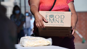 A person collects a box of food at a walk-up food distribution bank for people facing economic hardship or food insecurity, in a church parking lot in Los Angeles, California, August 10, 2020 amid the COVID-19 pandemic.