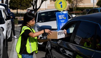 An employee delivers an Oculus VR headset curbside pickup order to a customer's vehicle at a Best Buy Co. retail store on Black Friday in Hawthorne, California, November 27, 2020.