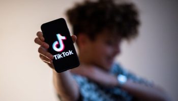 A teenager presents a smartphone with the logo of Chinese social network Tik Tok.