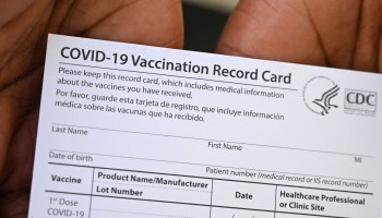 A worker displays a COVID-19 Vaccination Record Card.