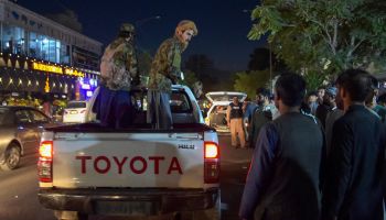 Taliban fighters stand on a Toyota pickup truck outside a hospital in Kabul.