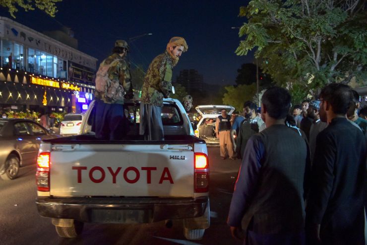Taliban fighters stand on a Toyota pickup truck outside a hospital in Kabul.