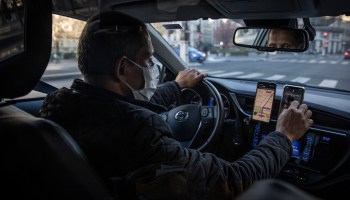 An Uber driver checks his phone as he drives.