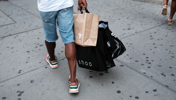 A person carrying purchases walks through a shopping district in New York.