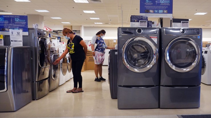 Shoppers look at washers and other large appliances in a department store.