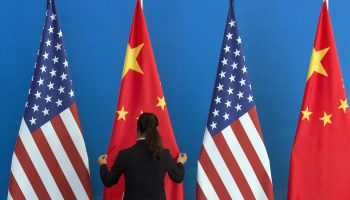 A Chinese woman adjusts a Chinese flag near U.S. flags before talks between those nations' representatives.