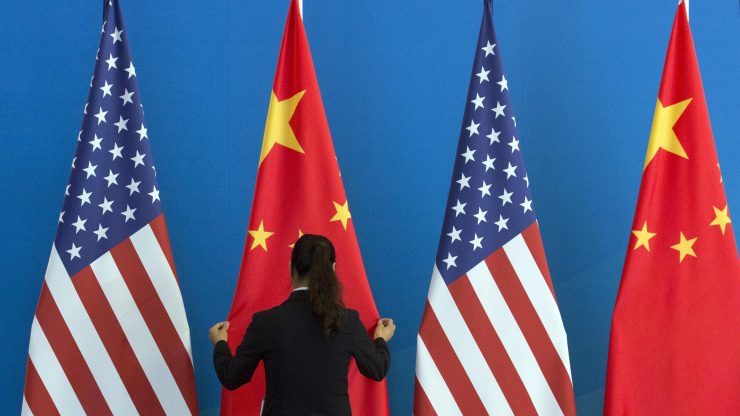 A Chinese woman adjusts a Chinese flag near U.S. flags before talks between those nations' representatives.