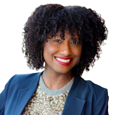 Dr. Tarika Barrett smiles for her headshot wearing a glittery top and navy blue jacket.