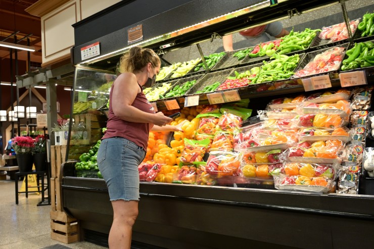 A woman selects produce at a supermarket.
