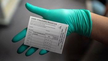 A health care worker displays a COVID-19 vaccine record card at the Portland Veterans Affairs Medical Center in Oregon.