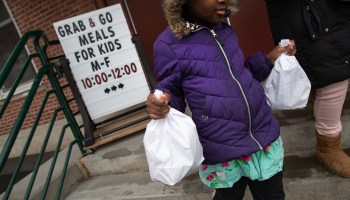 A student carries home bagged meals given out as part of Stamford Public Schools' "Grab and Go Meals for Kids" program, which is part of the city's response to the coronavirus pandemic on March 17, 2020 in Stamford, Connecticut.