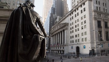 People walk past the New York Stock Exchange (NYSE) and a statue of George Washington at Wall Street on March 23, 2021 in New York City.