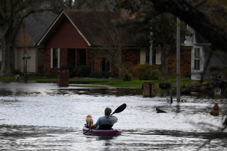 A person kayaks with a dog through flood waters past homes in LaPlace, Louisiana on August 30, 2021 in the aftermath of Hurricane Ida.
