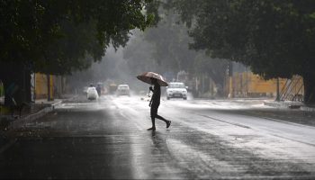 A person walks in the rain with an umbrella.