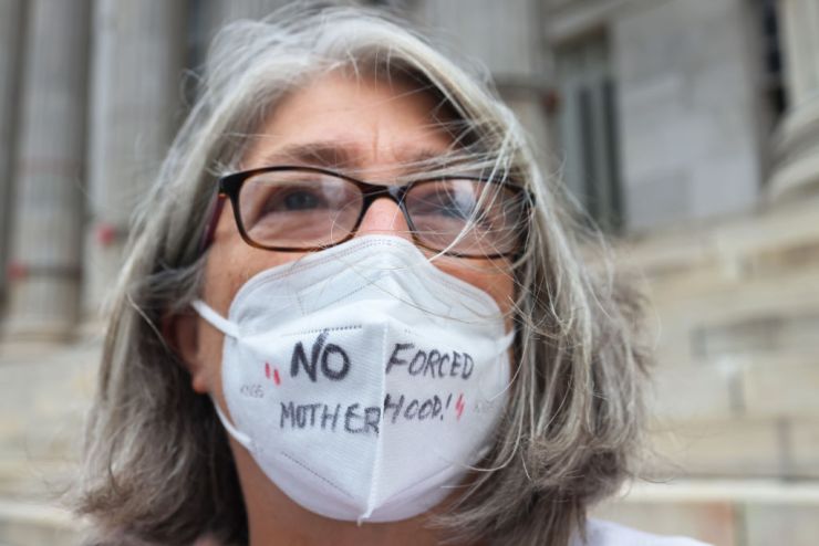 Demonstrator at a reproductive rights rally wearing a mask inscribed with the words " No Forced Motherhood."