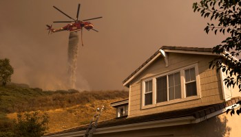 A firefighting helicopter makes a water drop near homes in California.