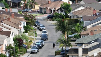 A man walks along a street in a neighborhood of single-family homes in Los Angeles, California.