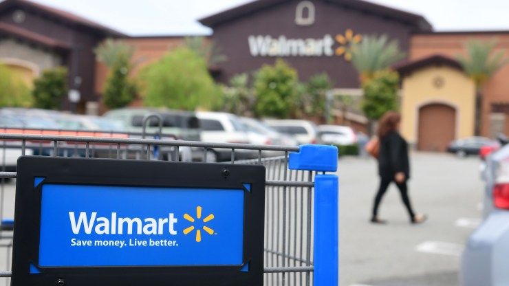 A woman walks past a shopping cart in the parking lot of a Walmart Supercenter in Rosemead, California on May 23, 2019.