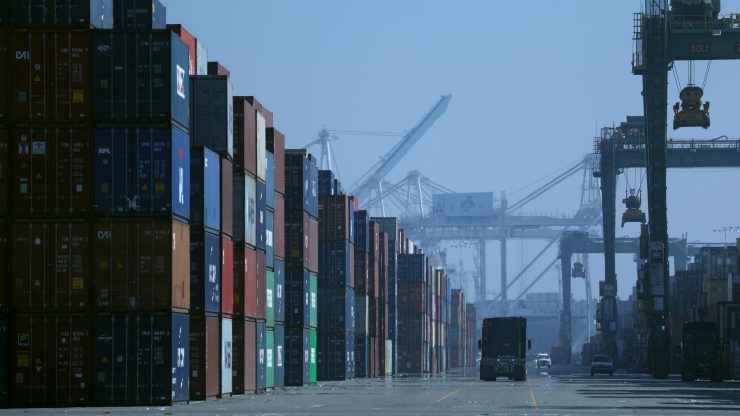 A truck drives past stacks of shipping containers at the Port of Oakland in California.