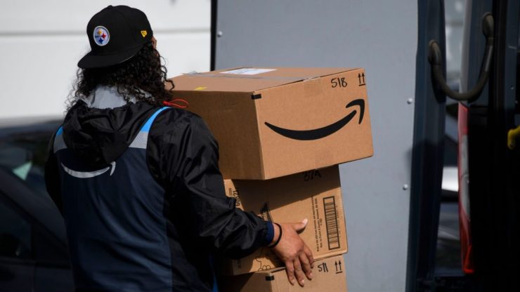 An Amazon delivery driver carries boxes into a van outside of a distribution facility in Hawthorne, California.